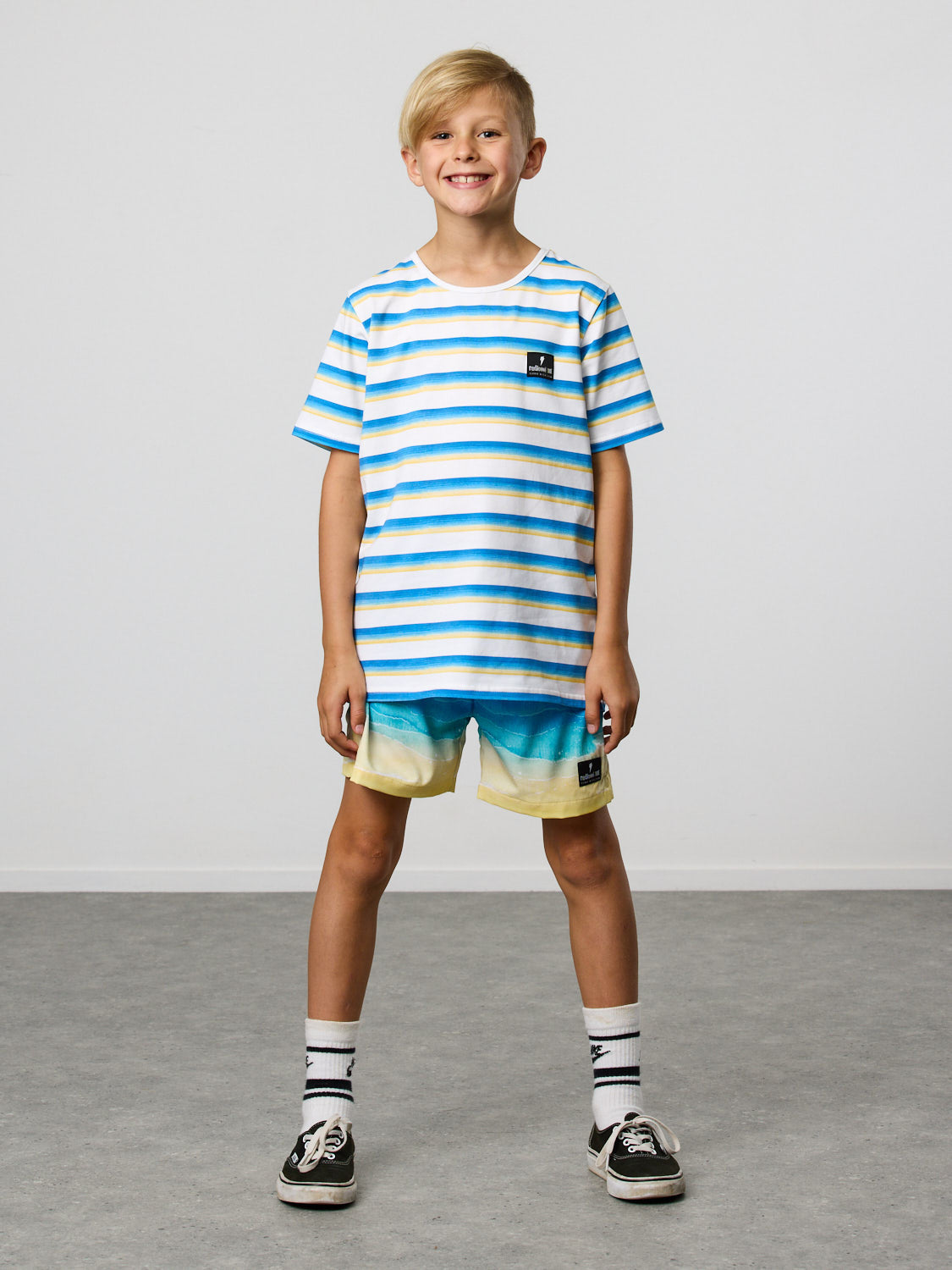 Radicool Kids beach stripe tee: Cotton / spandex tee in white with beach waves printed in horizontal stripes. Radicool Dude badge on chest. We love a stripe, even more when it’s the colours of the beach!  Fit is true to size.