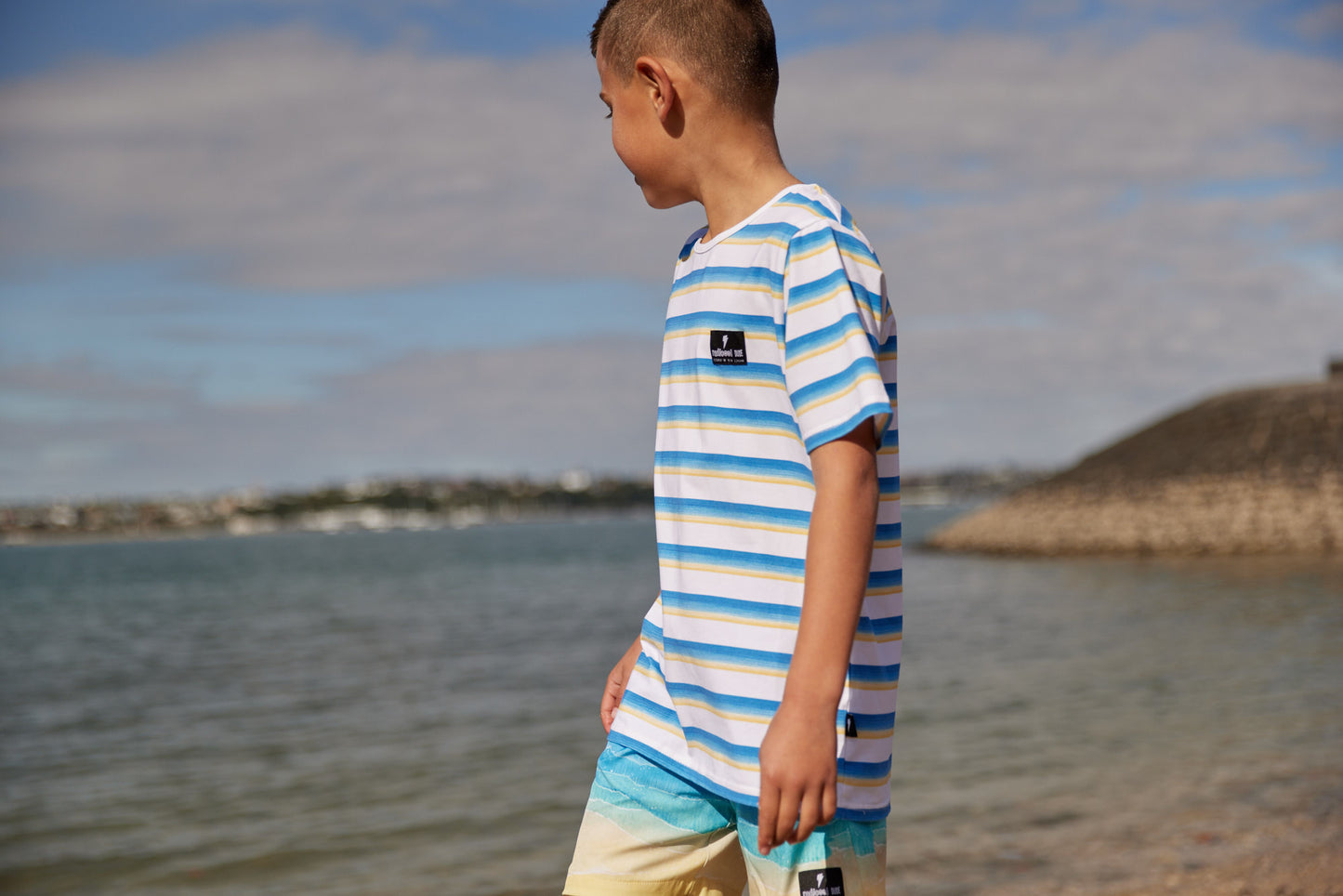 Radicool Kids beach stripe tee: Cotton / spandex tee in white with beach waves printed in horizontal stripes. Radicool Dude badge on chest. We love a stripe, even more when it’s the colours of the beach!  Fit is true to size.